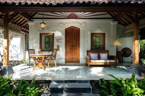 a patio with a table and chairs and a wooden door at Tandjung Sari Hotel in Sanur