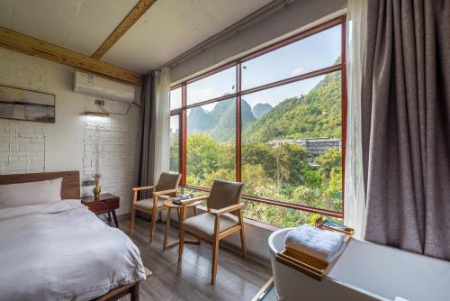 um quarto com uma cama e uma grande janela em Autumn Inn em Yangshuo