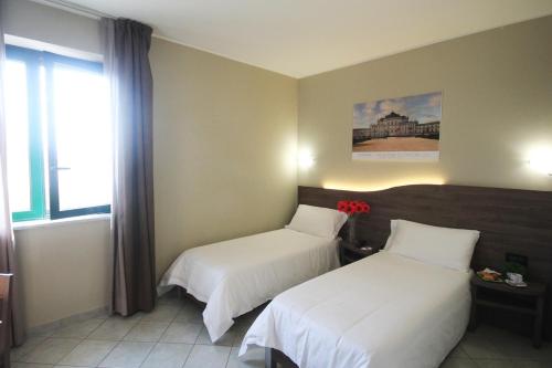 a hotel room with two beds and a window at Green Class Hotel Candiolo in Candiolo