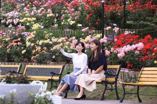 two women sitting on benches in front of flowers at Hotel Koyokan in Hanamaki