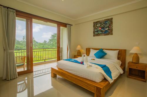 a bedroom with a bed and a balcony at The Carik Bisma Ubud in Ubud