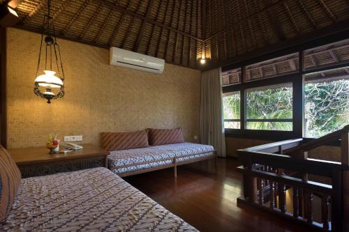 a room with a bed and a couch and windows at Tandjung Sari Hotel in Sanur