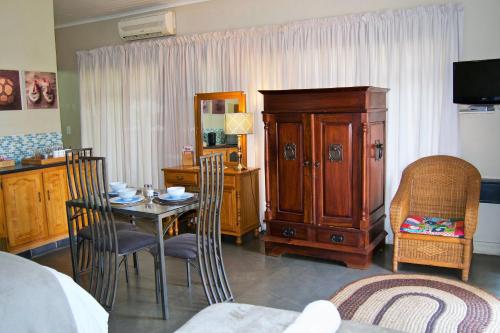 Habitación con mesa, armario y dormitorio. en Pumleni Guesthouse, en Hartbeespoort