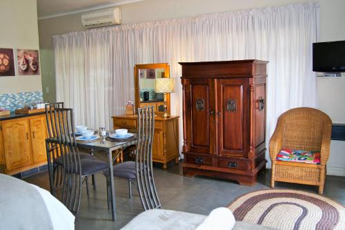 a room with a table and a cabinet and a bedroom at Pumleni Guesthouse in Hartbeespoort