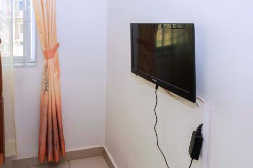 TV de pantalla plana colgada en la pared en Cityview Hotel Fort Portal, en Fort Portal