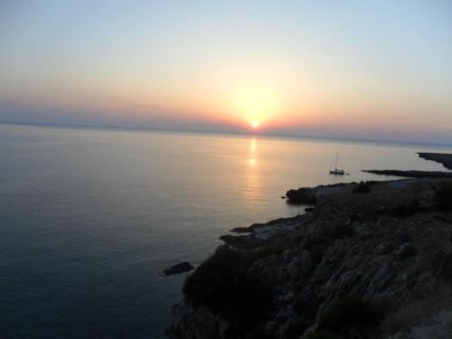 a sunset over the ocean with a boat in the water at Aurora Castelluzzo in Castelluzzo