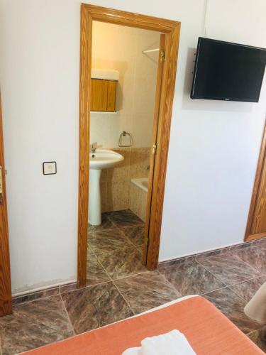 a bathroom with a toilet and a sink and a television at Hostal Restaurante Taibilla in Nerpio