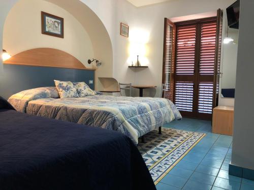 a hotel room with two beds and a bathroom at Diana Brown B&B Affittacamere in Lipari