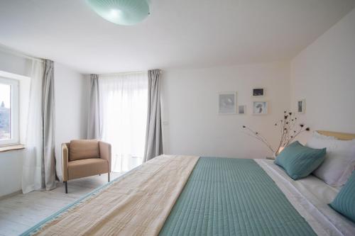 a white bedroom with a large bed and a chair at Villa Mamma Mia Oprtalj in Oprtalj