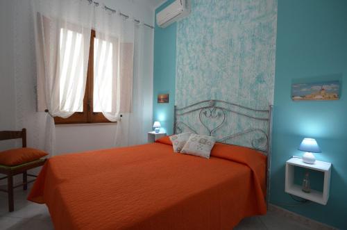 サン・ヴィート・ロ・カーポにあるCase vacanza Gioeleの青い壁のベッドルーム1室(オレンジ色のベッド1台付)