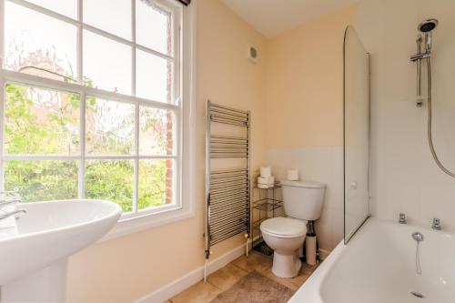 a bathroom with a tub and a toilet and a window at The Headington Shark House - Oxford in Oxford
