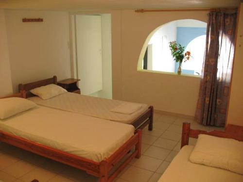 a bedroom with two beds and a window with a plant at Vesuvio Chora in Ios Chora