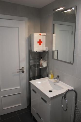 La salle de bains est pourvue d'un lavabo blanc et d'une marque de croix rouge sur le mur. dans l'établissement Casa Cimo Vila, à Provesende