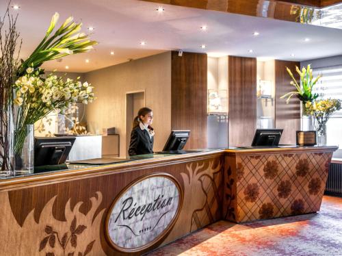 a woman standing at a reception desk in a hotel lobby at Tschuggen Grand Hotel - The Leading Hotels of the World in Arosa