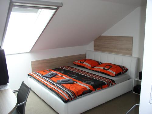 ein Schlafzimmer mit einem Bett mit orangefarbenen Kissen in der Unterkunft Ubytovani Bára Jižní Morava Břeclav Hodonín in Prušánky