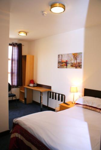 a hotel room with a bed and a desk at The Hindes Hotel in Harrow