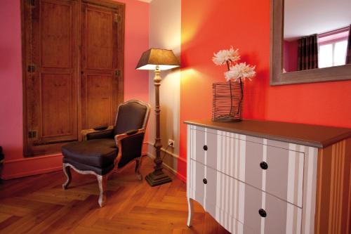 a room with a chair and a dresser and a lamp at Le Kléber Hôtel in Strasbourg