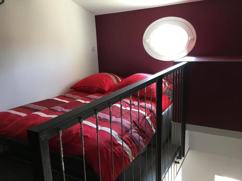 a bedroom with a bed with red comforter and a window at La maussanaise in Maussane-les-Alpilles