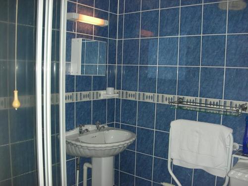 W wyłożonej niebieskimi kafelkami łazience znajduje się umywalka i toaleta. w obiekcie 7 Penhale w mieście Perranporth