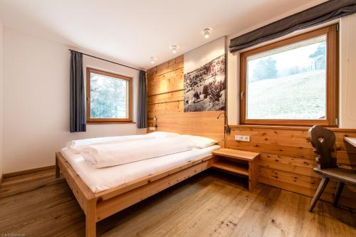 a bedroom with a bed and a desk and a window at Pension Haus Tirol in Laion