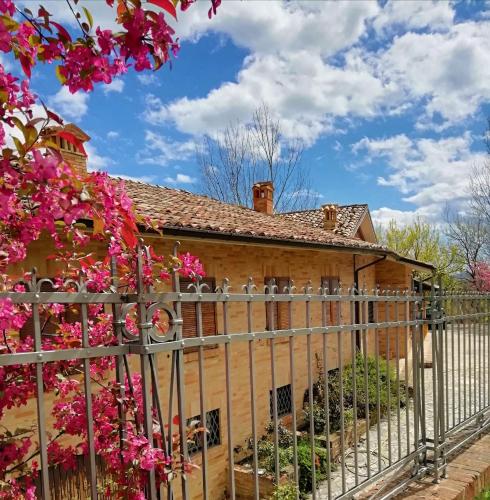 a fence in front of a house with pink flowers at Luci sui Monti in Sarnano