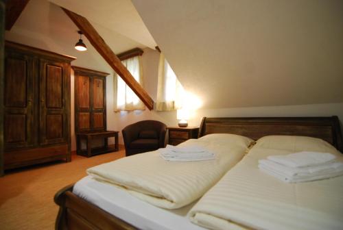 ein Schlafzimmer mit einem Bett mit weißer Bettwäsche und einem Stuhl in der Unterkunft Hotel 3 Gemsen in Mallnitz