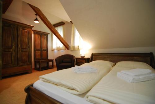 a bedroom with a bed with white sheets and a chair at Hotel 3 Gemsen in Mallnitz