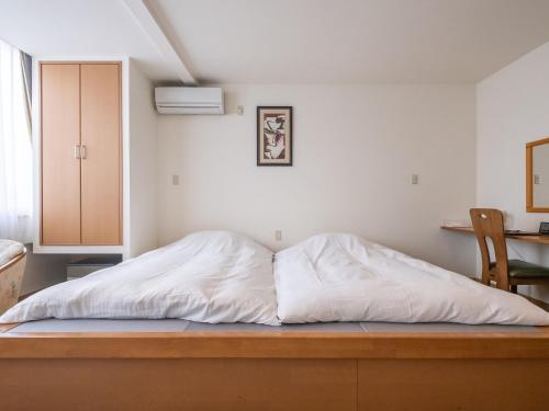 a bed with white sheets on a wooden floor in a room at HAKONE GORA ONSEN Hotel Kasansui in Hakone
