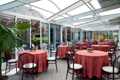 una sala da pranzo con tavoli e sedie in un giardino d'inverno di Hotel Felix a Rimini