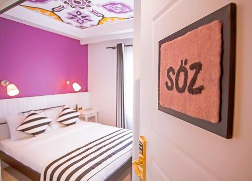 a bedroom with purple walls and a bed with striped pillows at Araf Hotel in Konya