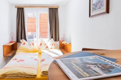 a bed with two pillows and a magazine on it at BaseCamp Apartments in Zermatt
