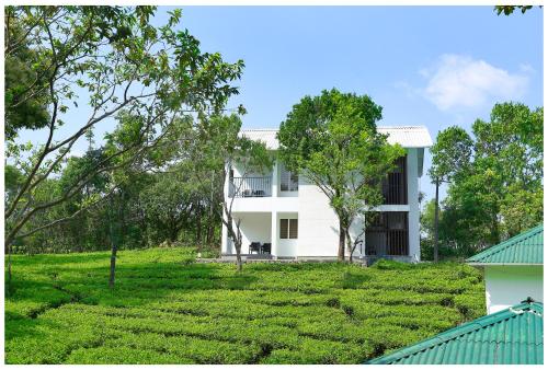 a white house on a green hill with trees at Holiday Vagamon in Vagamon