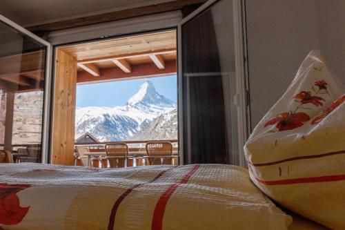 a bedroom with a view of a mountain through a window at BaseCamp Apartments in Zermatt