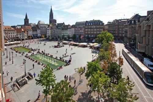 un grupo de personas caminando por una plaza en una ciudad en Le Kléber Hôtel, en Estrasburgo