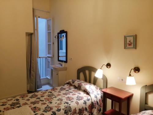 a bedroom with a bed and a table and a mirror at Pensión España in Cádiz