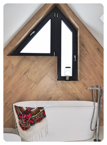 a bathroom with a large window above a bath tub at Biołe Izby in Poronin