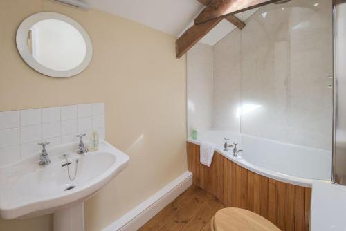 y baño con lavabo, bañera y espejo. en West Cottage, Southlands Farm, Gunnerton en Hexham