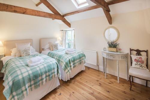 a bedroom with two beds and a table and a mirror at West Cottage, Southlands Farm, Gunnerton in Hexham