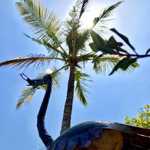 a statue of a bird standing next to a palm tree at Rock and Sea Resort in Watamu