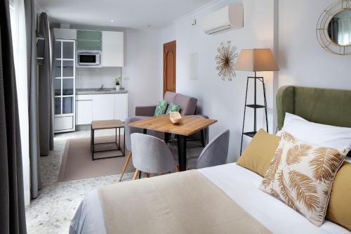 a bedroom with a bed and a table and a kitchen at Wanderlust Malaga Apartamentos - Atico in Málaga