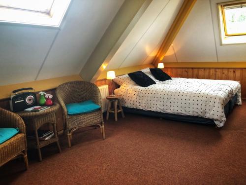 a bedroom with a bed and chairs in a attic at B&B Zandhuizen in Zandhuizen