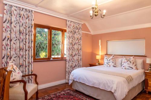 a bedroom with a bed and a chair and windows at Knightsbury Guest House in Cape Town