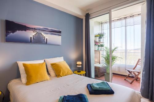 a bedroom with a large bed with yellow pillows at T2 avec loggia fleurie et ensoleillée in Toulon