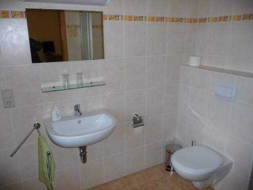 La salle de bains blanche est pourvue d'un lavabo et de toilettes. dans l'établissement Pension Spreewaldstube, à Vetschau/Spreewald