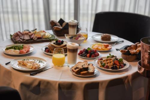 a table with plates of food and glasses of orange juice at Hotel Zhero – Ischgl/Kappl in Kappl