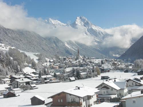 a town covered in snow with a mountain in the background at Hotel Schwarzer Adler in Pettneu am Arlberg