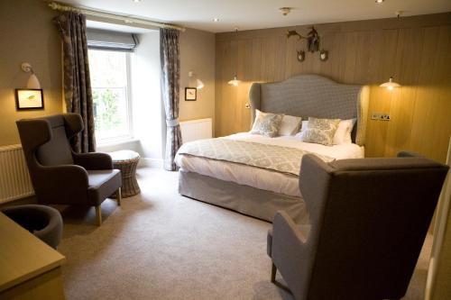 um quarto com uma cama, uma cadeira e uma janela em Saracens Head em Beddgelert