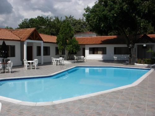 a swimming pool in a courtyard with tables and chairs at Hotel Villa Ricaurte in Girardot