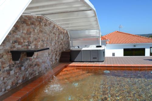 a swimming pool next to a brick building with a barbecue at Fazenda do Medronhal in Montemor-o-Novo