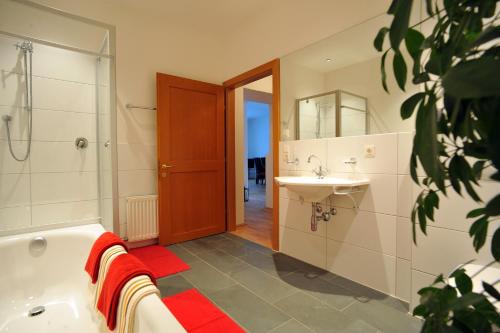ein Bad mit einer Badewanne, einem Waschbecken und einer Dusche in der Unterkunft Appartements Altes Gericht in Hopfgarten im Brixental